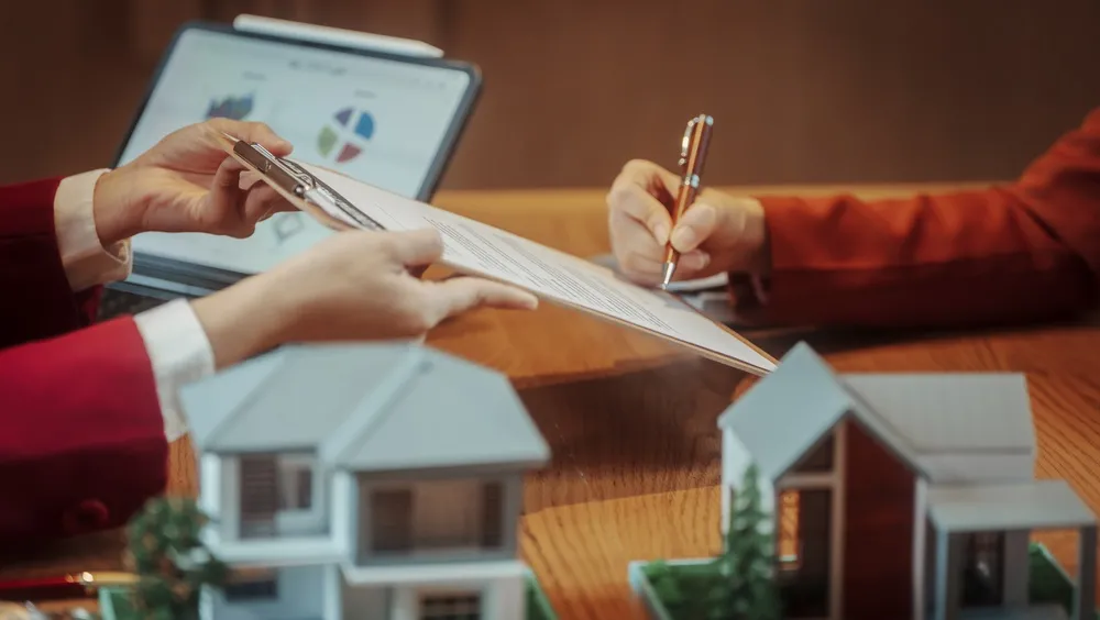 Hands,Signing,And,Reviewing,Real,Estate,Contract,At,Desk,With